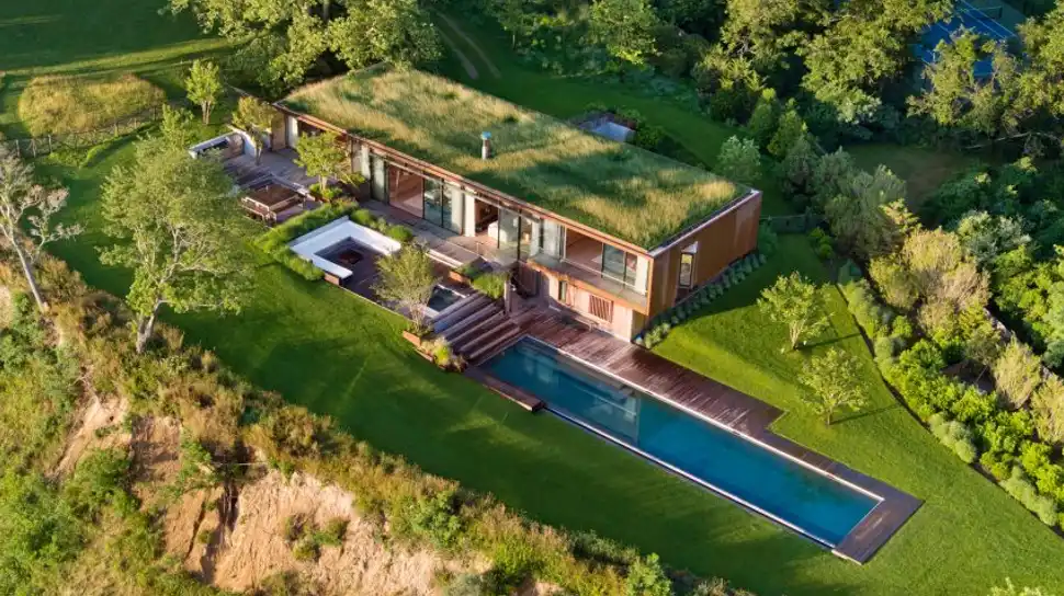 Peconic House with sustainable Hamptons-inspired interiors, featuring shrub-covered roof and stone accents.